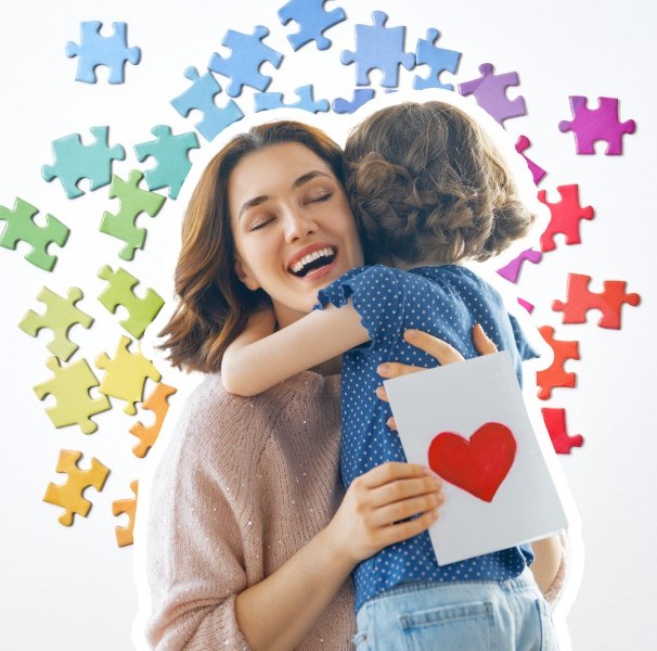 Mãe abraçando filho com peças de quebra-cabeça colorido (símbolo do autismo)